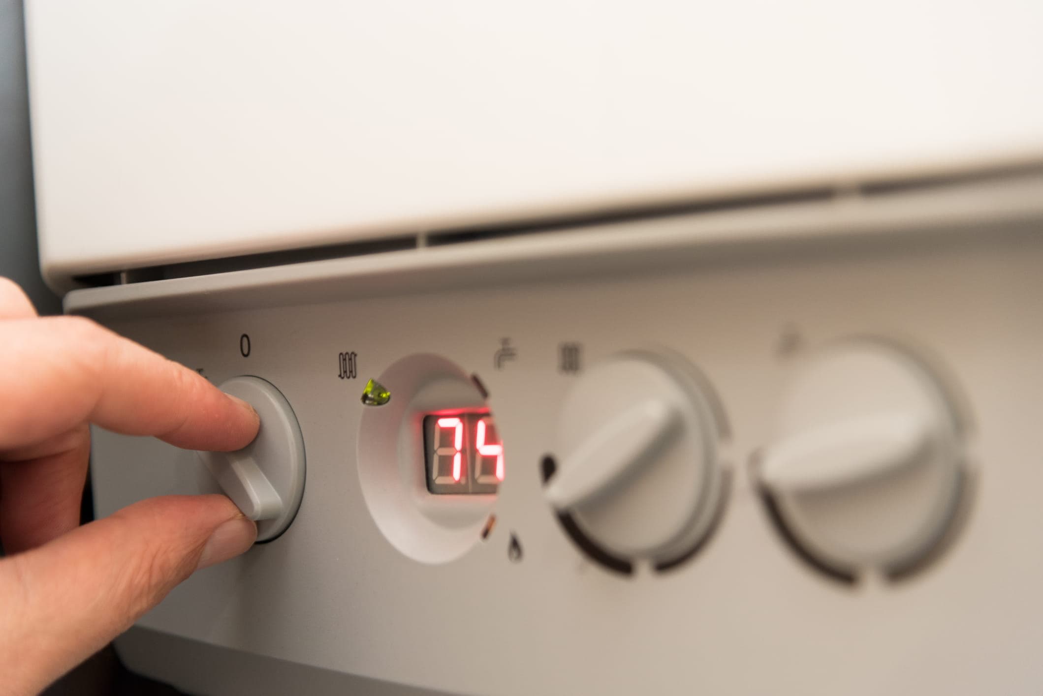 A hand adjusting a boiler control panel.