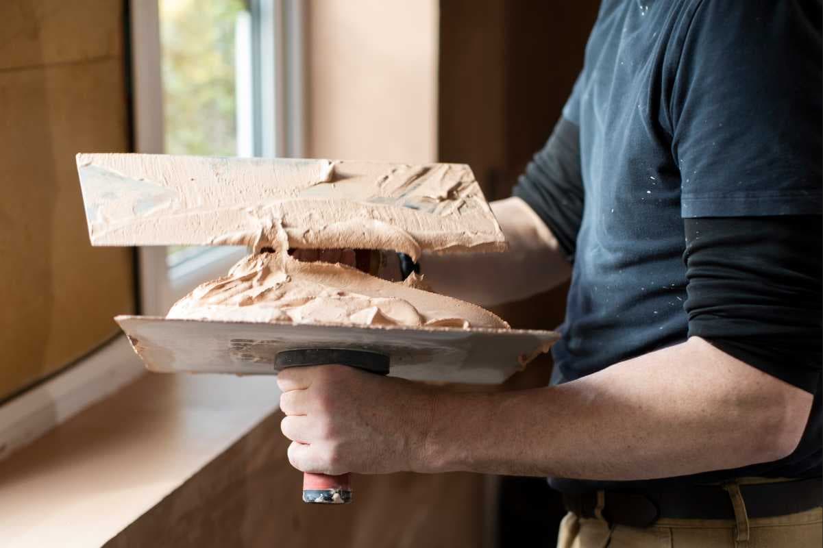 Plasterer holding a hawk and trowel with fresh plaster.