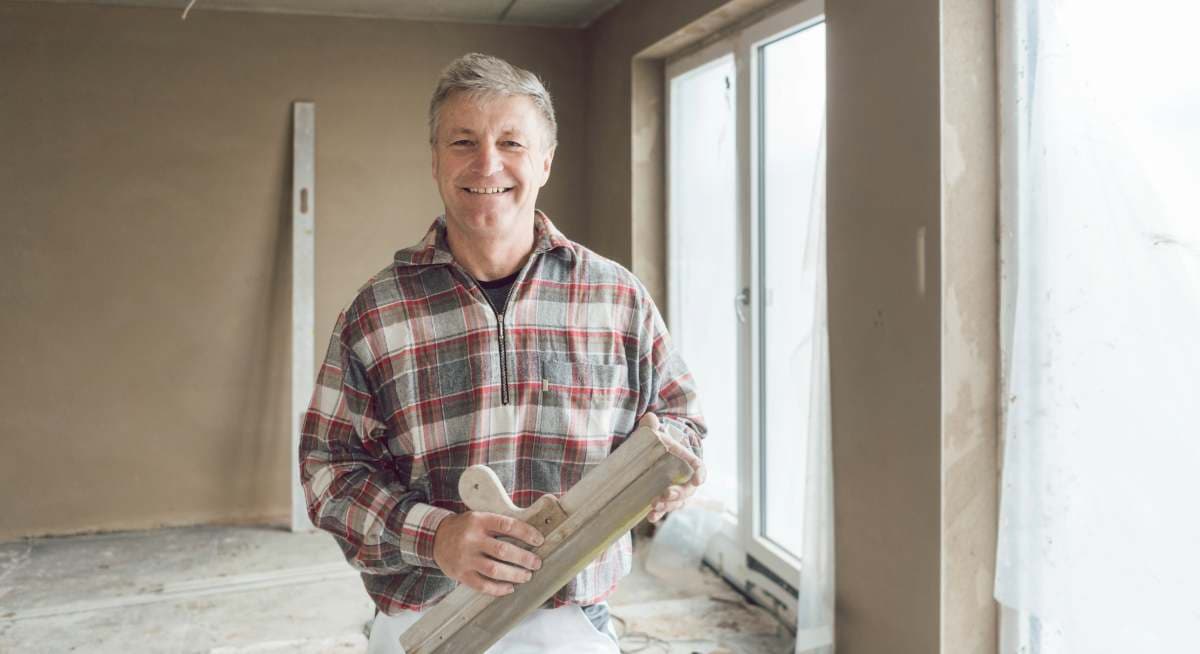 Plasterer standing in a freshly plastered room.